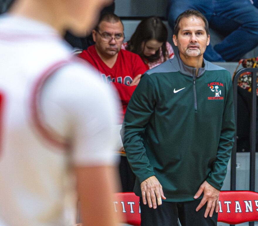 A basketball coach watches a player