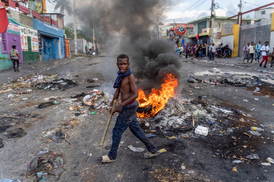 A man walks past a burning barricade during a protest against Haitian Prime Minister Ariel Henry, calling for his resignation, in Port-au-Prince.