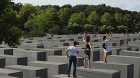 Visitors photograph each other while standing on concrete slabs at the Holocaust Memorial in Berlin in 2016.