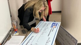 The United Way's Ashley Johnson fills out oversized checks during the awarding of Empowering Employment grants