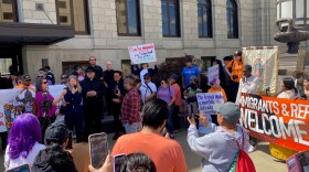 a groups of immigrant supporters rallies outside the federal courthouse in des moines with a sign that says "immigrants and refugees welcome"