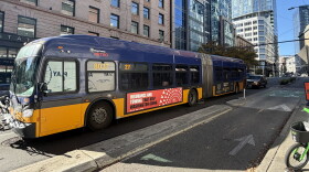 A photo of a yellow and purple King County Metro bus in downtown Seattle. 