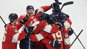 Florida Panthers center Sam Reinhart, far right, is mobbed by teammates after he scored during an overtime period of Game 4 during the Eastern Conference finals of the NHL hockey Stanley Cup playoffs to beat the New York Rangers, Tuesday, May 28, 2024, in Sunrise, Fla. (AP Photo/Wilfredo Lee)