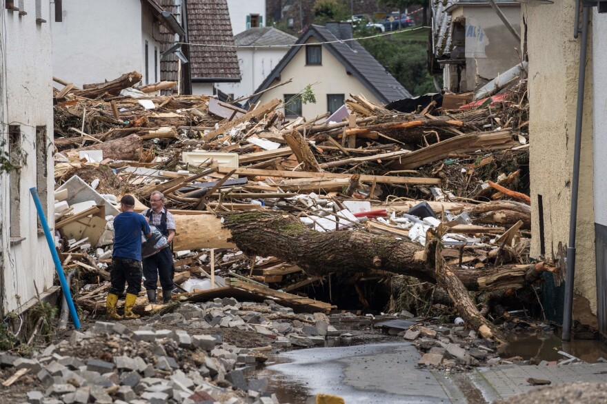 Two men try to secure goods from next to the debris of houses destroyed by the floods in Schuld near Bad Neuenahr in western Germany on Thursday.