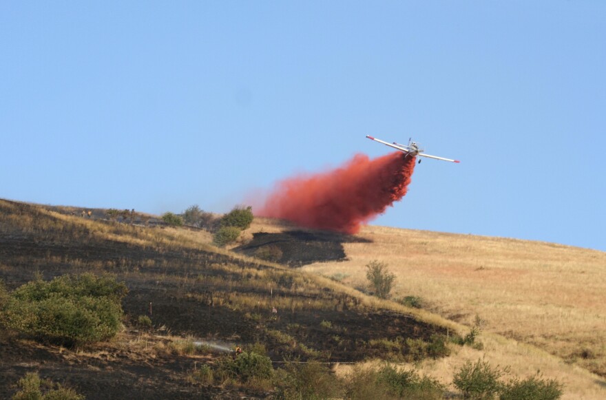 An airplane drops retardant on a grass fire burning on Mount Sentinel in Missoula, MT, August 20, 2020.