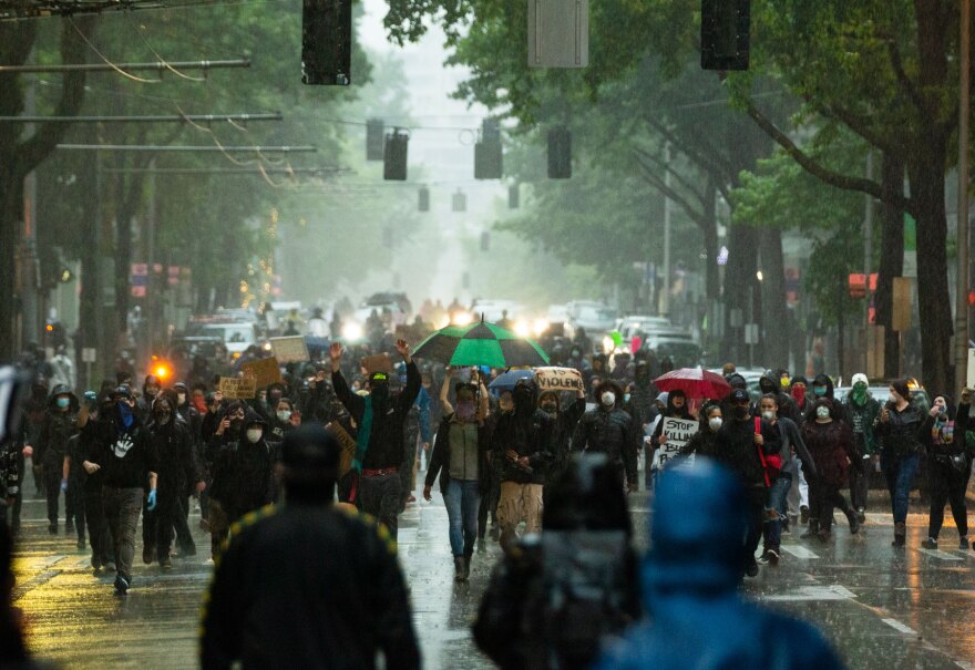 Seattle protesters march in the rain on the first day of widespread demonstrations in response to the killing of George Floyd in Minneapolis.