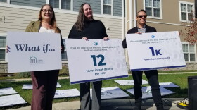 Three people hold signs. 