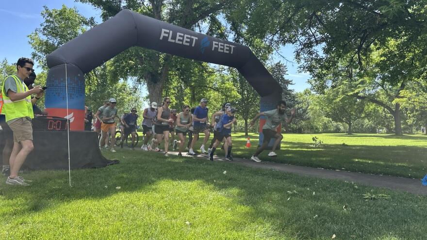 Runners are taking off to run the race after the horn blows, and there is an inflatable above them that says "Fleet Feet".