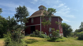 A red, octagonal barn is seen among greenery. 