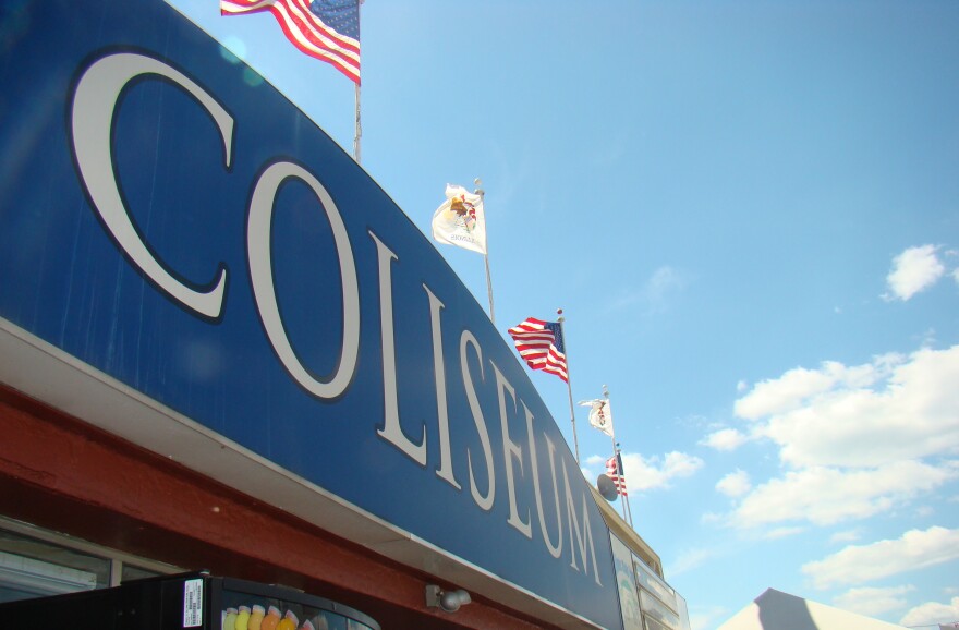 The coliseum at the state fair with flags waving above it.