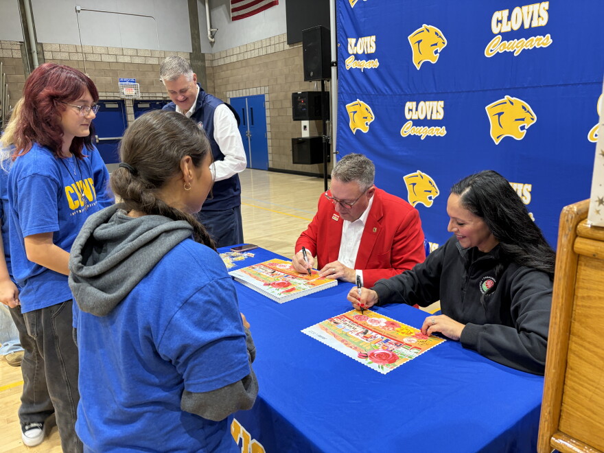 Terry Madigan, Tournament of Roses president, and Esmeralda Rocha Lozano, Clovis High music director, sign Rose Parade posters for band students.