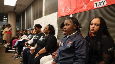 Bailey Watson, a student at the Leah Chase School, sits with her teachers at a New Orleans school board meeting after asking the board to keep the school open.