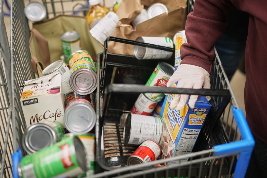 A line of people and cars outside a large brick building that serves as a food pantry 