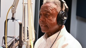 A man sitting at a microphone in a studio setting.