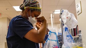 A medical worker puts on a mask before entering a negative pressure room with a COVID-19 patient in the ICU ward at UMass Memorial Medical Center in Worcester, Mass., last week.