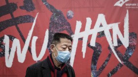 A man in Wuhan, China, the epicenter of the current coronavirus outbreak, walks by a local mural.