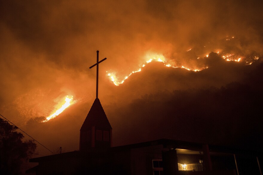 Flames from a wildfire advance down a hillside near the Springs of Life Church in Casitas Springs, Calif., on Tuesday.