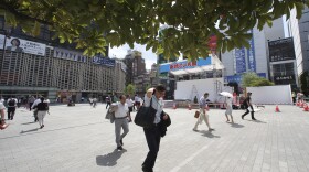People make their way in the scorching heat at a business district in Tokyo, Monday, July 23, 2018.