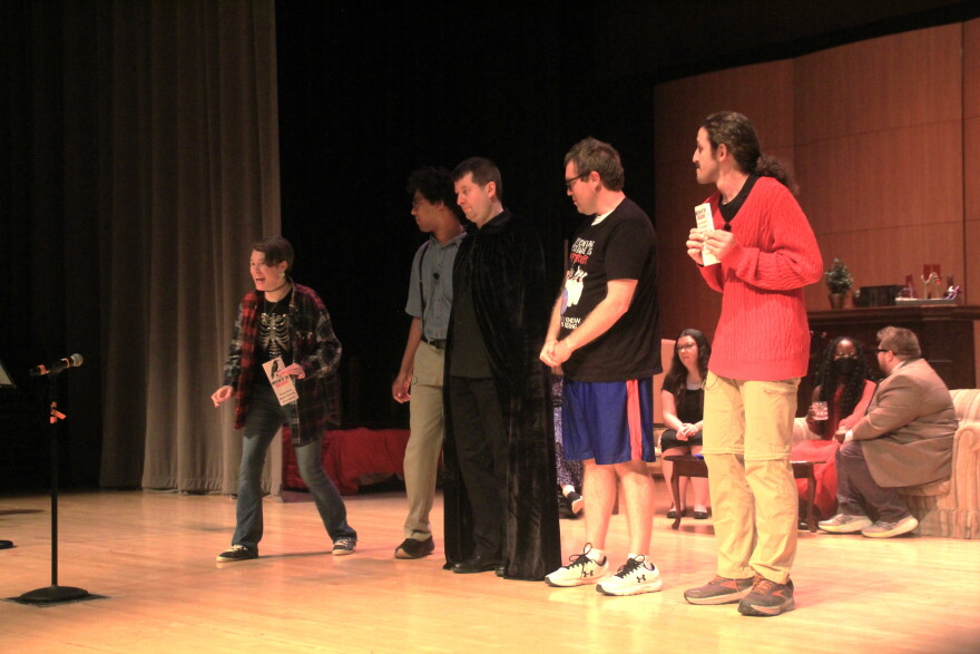 Cast members rehearse on stage inside a theater.   