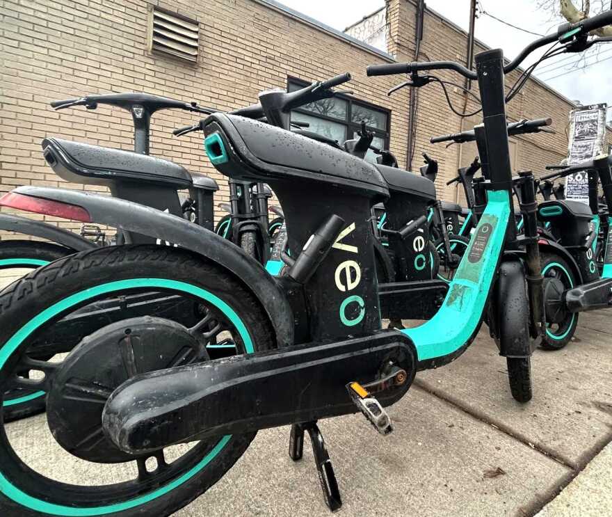 Close up view of a Veo rental bike at a stand on a city sidewalk in Syracuse