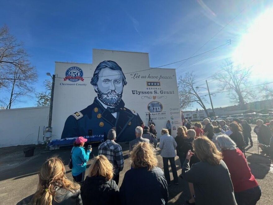 A crowd looks up at a mural of Ulysses S. Grant.