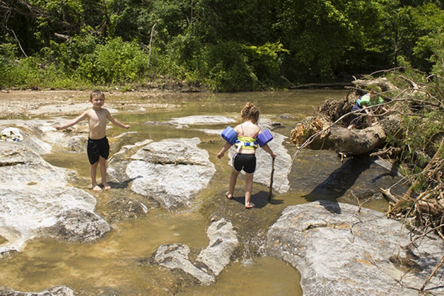 Children play in a small tributary of the Illinois River near Tahlequah, Okla., in May 2015. 