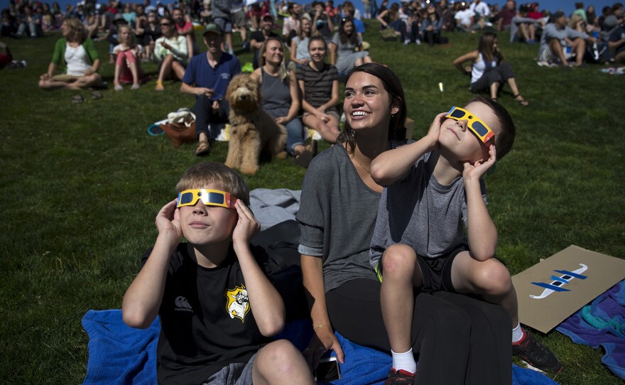 From left, Wyatt Godwin-Austen, 10, Megan Cordell, and Hunter Godwin-Austen, 8, watch the solar eclipse from Gas Works Park on Monday, August 21, 2017, in Seattle. KUOW Photo/Megan Farmer