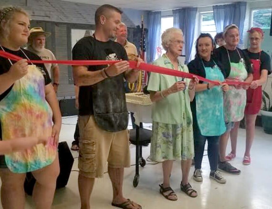 Gwen Johnson’s mother, Mabel, center, cuts the ribbon for the solar installation at Hemphill Community Center.