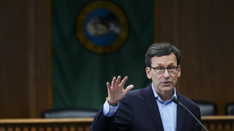 Gov. Bob Ferguson of Washington raises his hand as he talks.