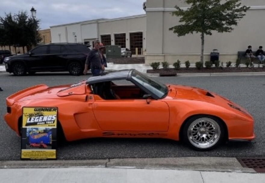 This orange Porsche Spyder was on display at the Sixth Annual International Car Show at Butler Town Center in Gainesville on Saturday, Oct. 17, 2026. The sign at left identifies it as having been selected for the 2025 Hot Wheels Legends Tour. (Samuel Rappoport/WUFT News)