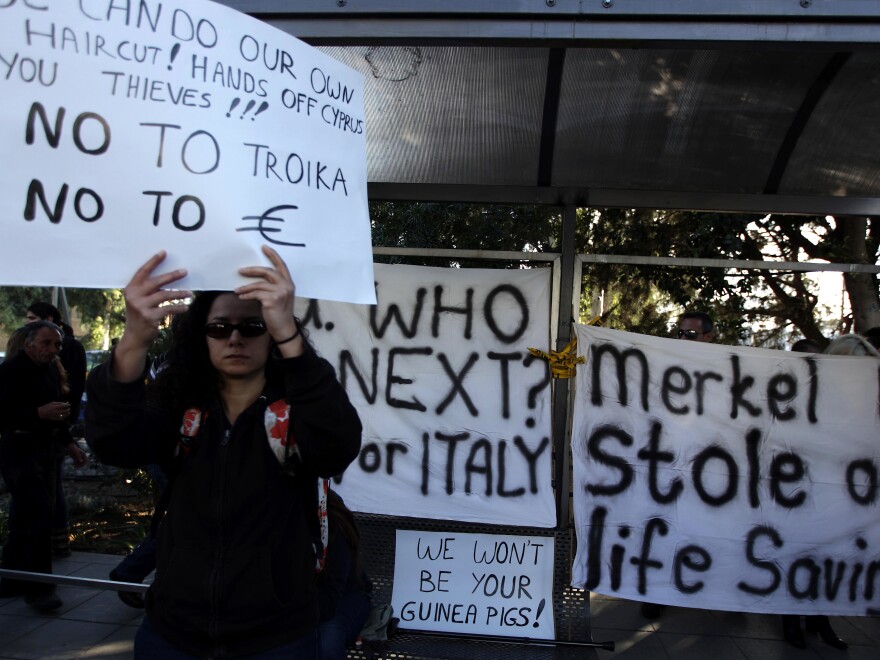 A Cypriot woman holds a sign during a protest against an EU bailout deal outside the Parliament in Nicosia on Monday.