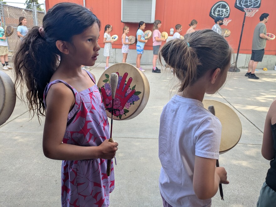 Students play their drums, sing in nsyilxcən—Colville Okanogan Salish—and face east toward the sun at the start of their school day in a common area of the Salish School of Spokane on July 2, 2025.