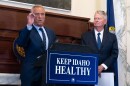 Two men in suits gather around a podium in front of a ceremonial fireplace.