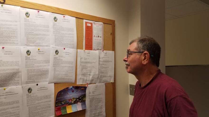 Bizmar Gonzalez scans a job postings board. He's a retired teacher from Puerto Rico looking for work now in central Florida. Photo by Crystal Chavez.