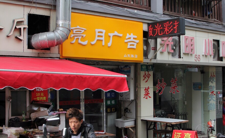 Qiu grew up in the house above the yellow sign here in the heart of Shanghai.