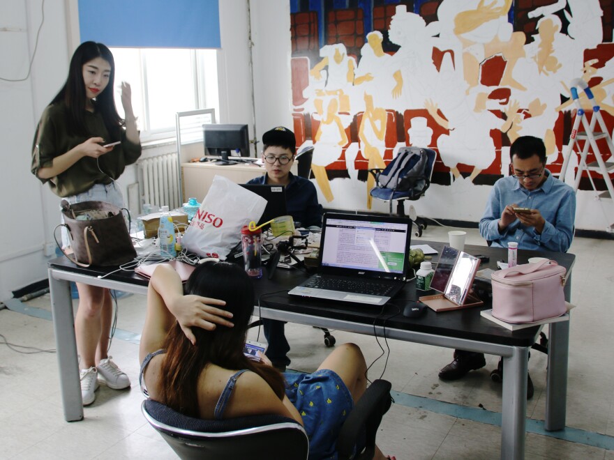 Huang Xian'er (left) looks at her smartphone at the Beijing-based Internet talent company where she works.