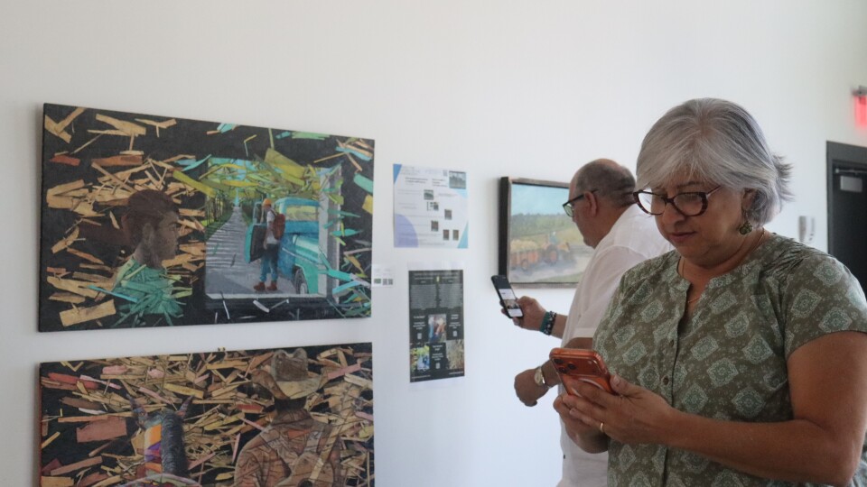 Artist Gloria Astreaga and poet Georgie Medina Marcano looking at their phones in an art gallery