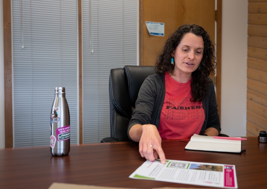 A woman wearing a cardigan points to a piece of paper
