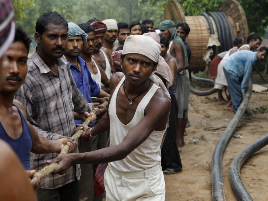 Indian workers pull a rope to tug an electrical cable at a construction site in New Delhi, India on Sunday.