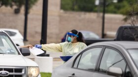 A worker handles paperwork at CommUnityCare's drive-thru coronavirus testing site at the Hancock Center.