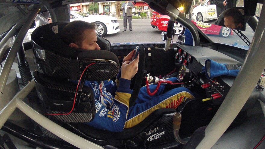 Brad Keselowski looks at his smartphone during a NASCAR champions parade in Las Vegas in November.