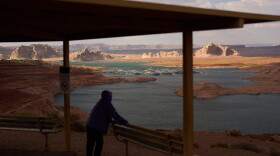 FILE - A person stands at an overlook near the Wahweap Marina on Lake Powell at the Glen Canyon National Recreation Area, July 15, 2026, near Page, Ariz. (AP Photo/John Locher, File)