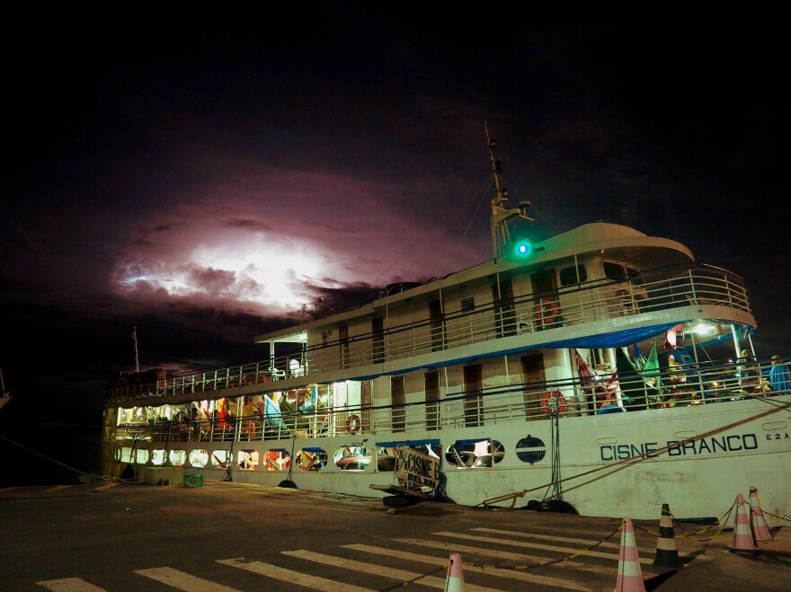 The White Swan docks for an overnight stop in the industrial city of Santarém in the northern Brazilian state of Pará. Heat lightning flashes through the night as passengers sleep in hammocks and crew fetch new cargo for the next leg of the journey.