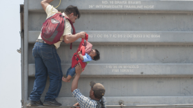 A Central American toddler migrant being lifted onto a freight train in Mexico during his family's trek to the U.S. border in 2014.