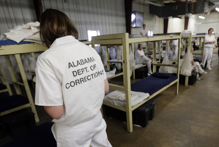 An inmates reads her Bible, left, as other inmates sit on their bunks in a dorm at Tutwiler Prison for Women in Wetumpka, Ala., Monday, Sept. 23, 2013. A hearing was held Tuesday at the prison before U.S. District Judge Myron Thompson about life under the Alabama prison system's policy of keeping HIV-positive inmates segregated from other inmates. The purpose of the hearing was for Thompson to determine if a proposed settlement of a lawsuit challenging the policy was fair. (AP Photo/Dave Martin)