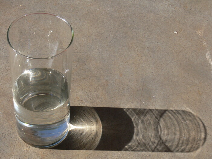 A glass of water sits on a grey surface.