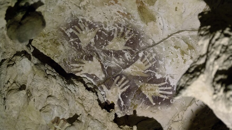 Archaeologists found hand stencils made by blowing liquid ochre over hands placed on cave rocks. The earliest hand stencils are more than 50,000 years old.