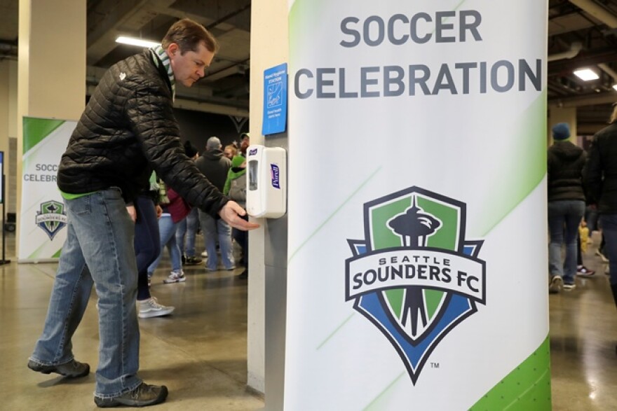 A man makes use of a hand-sanitizing station at CenturyLink Field prior to an MLS soccer match between the Seattle Sounders and the Chicago Fire, Sunday, March 1, 2020, in Seattle. 