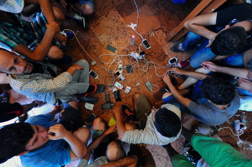 Migrants charge their cellphones at the Keleti railway station in Budapest last month. "If technology can play a role in making [their] journeys a bit less precarious and harrowing, and help refugees stay connected," says Kate Coyer, "then they're worth investing in."