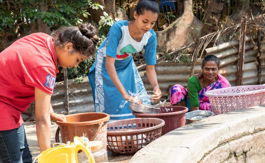 Teenager Shraddha Tandel washes cooking utensils at a communal village well.